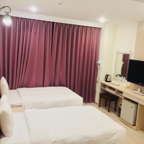 a hotel room with two beds and a red curtain at Kousin Hotel in Kaohsiung