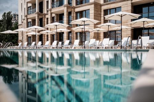 - une piscine avec des chaises et des parasols en face d'un bâtiment dans l'établissement Cabacum Plaza Beach Apartments - High-Speed WiFi, aux Sables d'or