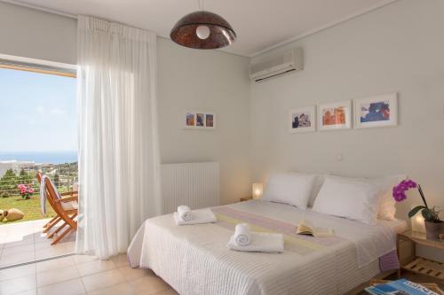 a white bedroom with a bed and a balcony at Comfortable house with amazing view in Anavyssos