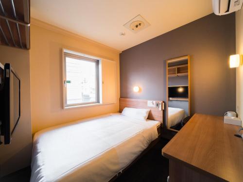 a small bedroom with a bed and a window at Super Hotel Inn Kurashiki Mizushima in Kurashiki