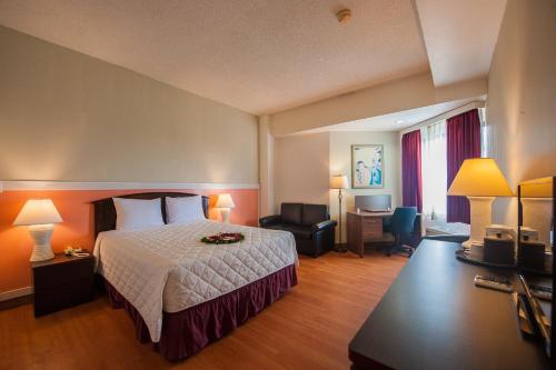 Habitación de hotel con cama y silla en Grand Plaza Hotel, en Tumon