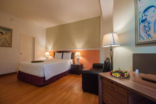 a hotel room with a bed and a television at Grand Plaza Hotel in Tumon