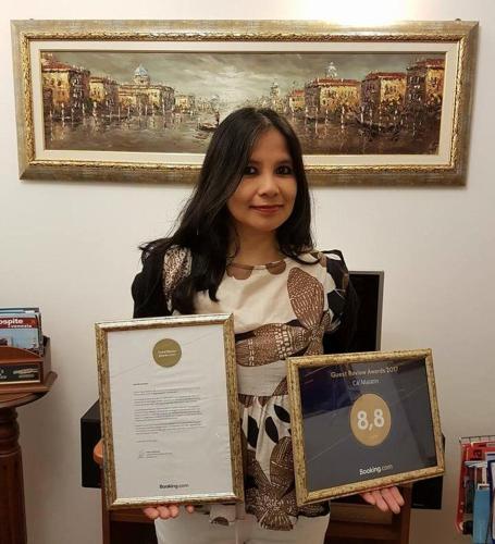 a woman holding two certificates in front of a painting at Ca' Malatin in Venice