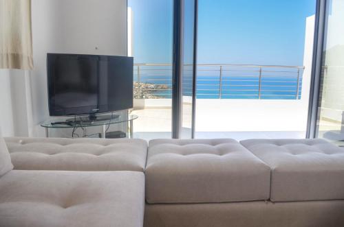 a living room with a couch and a flat screen tv at Villa Xenia Stalis in Stalida