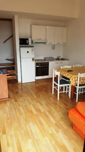 a kitchen and dining room with a table and a kitchen with white appliances at Apartments Adriatic 2 in Selce