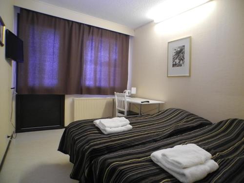 a hotel room with a bed with towels on it at Hotelli Anna Kern in Imatra