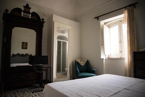 1 dormitorio con cama, espejo y silla en B&B Valle Allegra, en Gravina di Catania
