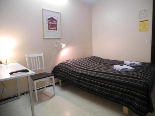 a bedroom with a bed and a desk and a table at Hotelli Anna Kern in Imatra