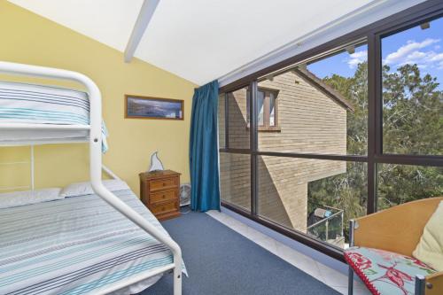 een slaapkamer met een stapelbed en een groot raam bij Beachpark 56 58 Pacific Drive in Port Macquarie