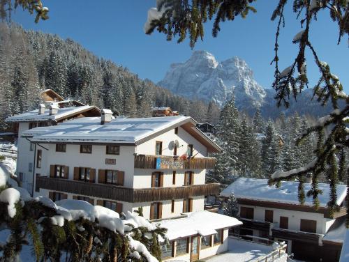 a building in the snow with a mountain in the background at Hotel Garni Ongaro in Selva di Cadore