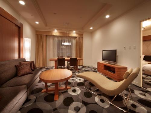 uma sala de estar com um sofá e uma televisão em Hotel Metropolitan Yamagata em Yamagata