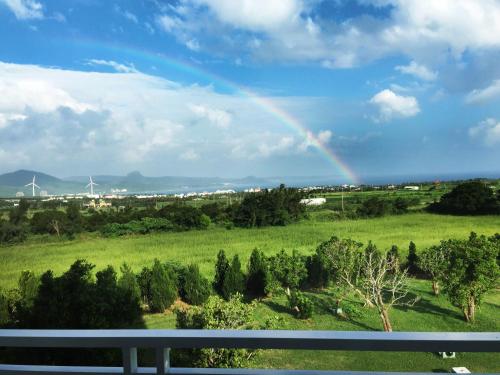 a rainbow over a green field with trees and windmills at Coral B&B in Hengchun