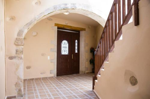 an empty hallway with a wooden door and stairs at Villa Cardia in Kiriánna