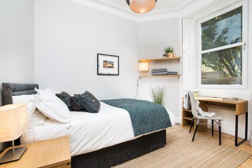 a bedroom with a bed and a desk and a window at Beautiful, Traditional 2 Bedroom Main Door Flat in Edinburgh