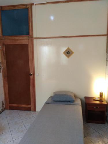 a bedroom with a bed and a door and a lamp at Edificio Magico in Tarrafal