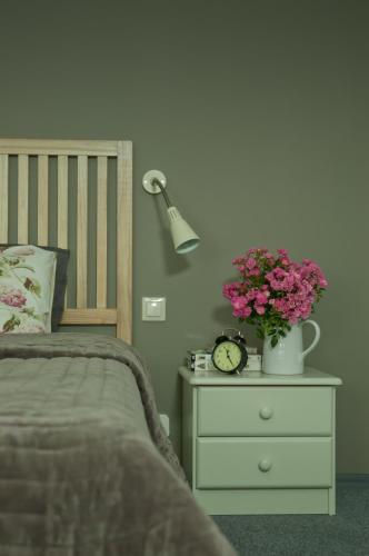 a bed with a night stand with a clock and flowers at Hotel Flora in Łódź
