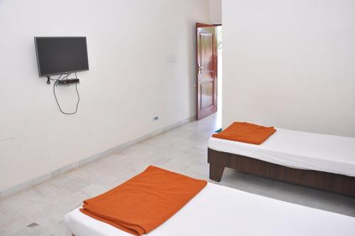 two beds in a room with a tv on the wall at Hotel SunShine Palace in Chotila