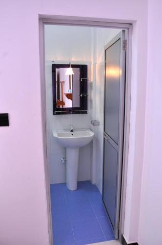 a white bathroom with a sink and a mirror at Hilton Cottage in Trincomalee