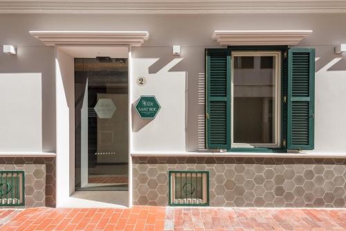 a building with green shutters and a window at Boutique Hotel Sant Roc & Spa in Mahón