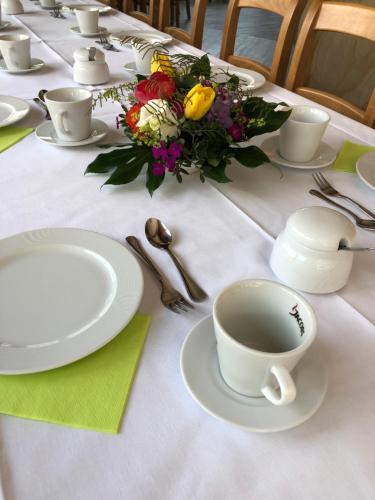 a table with white plates and a cup of coffee at Hotel Zwei Länder in Apolda