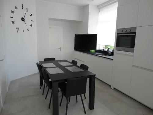 伊普爾的住宿－Aan de vestingrand，厨房配有黑色的桌子、椅子和时钟
