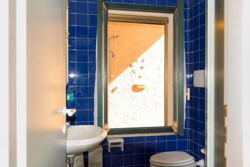 a blue tiled bathroom with a sink and a toilet at Appartamento Poggio al Sole in Capoliveri