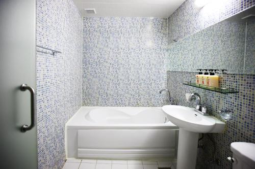 a bathroom with a white tub and a sink at Q Hotel in Paju