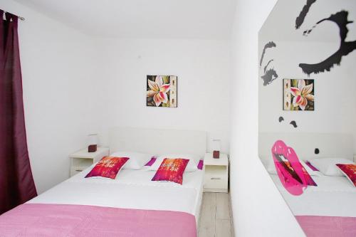 two beds in a white room with pink and purple pillows at Vito in Bibinje