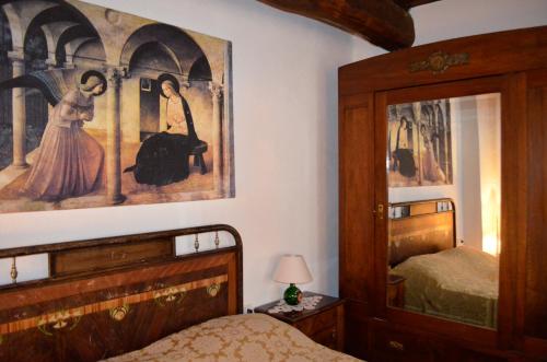 1 dormitorio con 1 cama y una gran pintura en la pared en Casa Portone Paola, en Campiglia dʼOrcia
