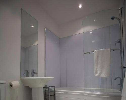 a white bathroom with a sink and a shower at Aberdeen Serviced Apartments - The Lodge in Aberdeen