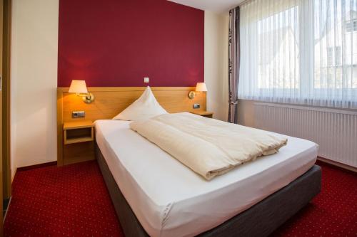 a bedroom with a large white bed with a red carpet at Hotel Merle in Bruttig-Fankel