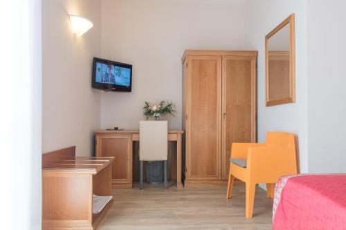 a room with a bed and a desk and a television at Hotel Antica Stallera in Cannobio