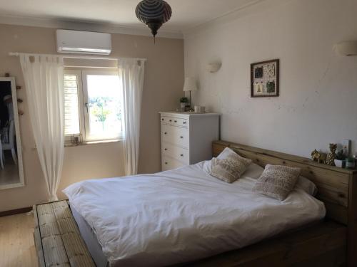 een slaapkamer met een wit bed en een raam bij Cegonha Villa powered by Cegonha Resort- Private swimming pool & air con in Albufeira