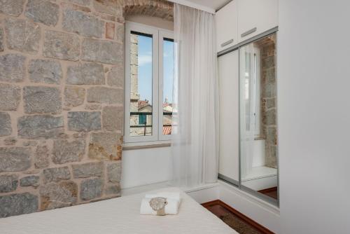 Habitación con pared de piedra y ventana. en Fairy Of The Seas Apartments, en Split