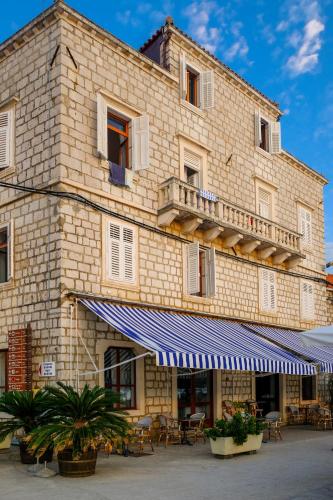 a building with a blue awning in front of it at Hotel Glavovic in Lopud Island
