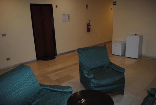 two green chairs and a table in a room at Hotel South Paradise in Palmi