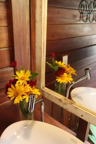 a bathroom with a sink with flowers in a mirror at Pousada Vayú in Icaraí