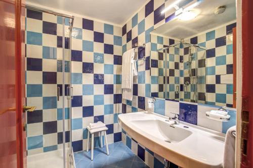 un bagno blu e bianco con lavandino e doccia di Marina Club Hotel a Baia Domizia