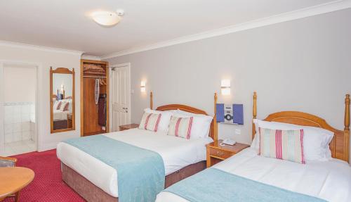 a hotel room with two beds and a table at Abbey Lodge in Killarney