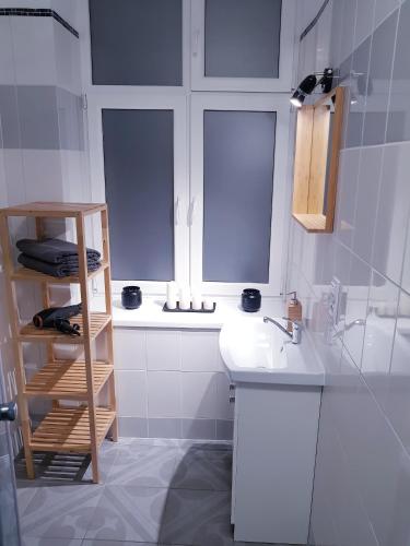 a white bathroom with a sink and two windows at Apartamenty Równa in Kielce