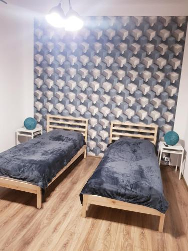 two beds in a room with a wall with hearts at Apartamenty Równa in Kielce