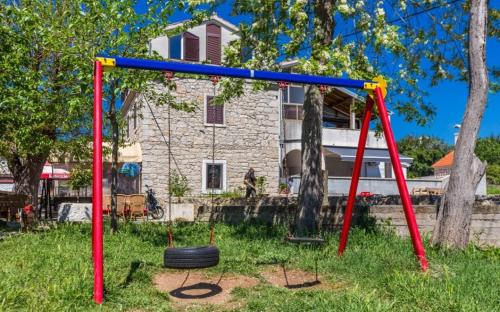a swing set in a yard in front of a house at Slanac 3 in Veli Iž