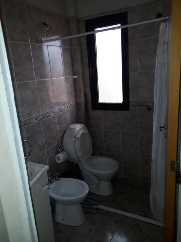 baño con aseo y lavabo y ventana en Complejo Camila en Villa Carlos Paz