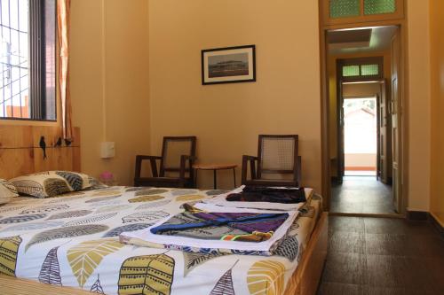 a bedroom with a large bed and two chairs at Sai Homestay in Malvan