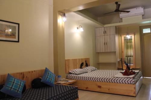 a room with two beds and a couch in it at Sai Homestay in Malvan