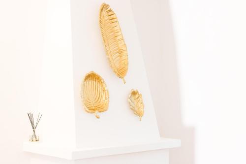 two gold feather wall hooks on a white shelf at Herdade da Sanguinheira in Longomel