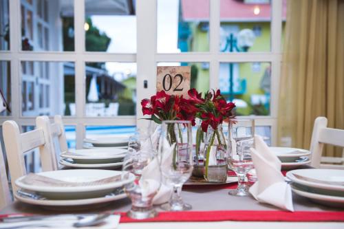 a table with white plates and red flowers on it at Hotel Pousada da Neve in Nova Petrópolis