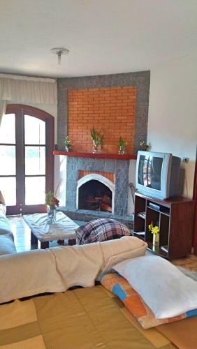 a living room with a tv and a fireplace at Casa de Campos do Jordão in Campos do Jordão