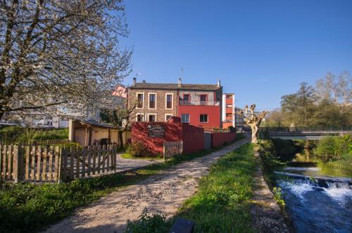 a house next to a river with a fence at La Casona de Sarria in Sarria