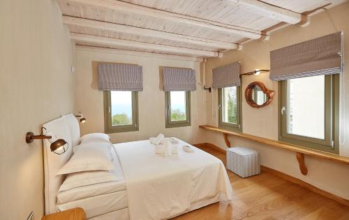 1 dormitorio con 1 cama con sábanas blancas y ventanas en Sunrise Tsagkarada en Tsagarada